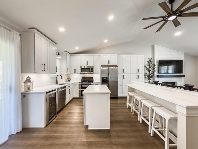 kitchen with a kitchen island, ceiling fan, light countertops, a sink, and stainless steel appliances