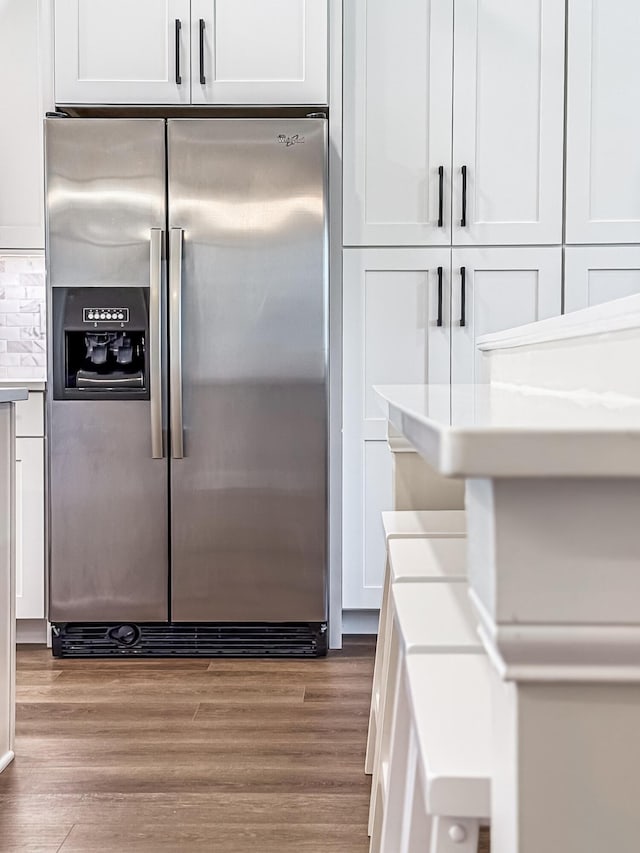 interior space featuring stainless steel fridge, light countertops, wood finished floors, and white cabinetry