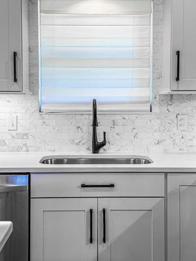 kitchen with a sink, light countertops, tasteful backsplash, and dishwasher