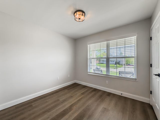 unfurnished room featuring dark wood-style flooring and baseboards