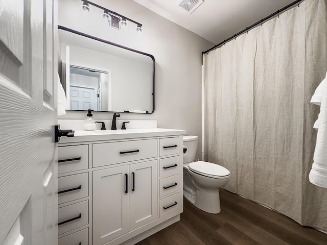 full bathroom featuring visible vents, vanity, curtained shower, wood finished floors, and toilet