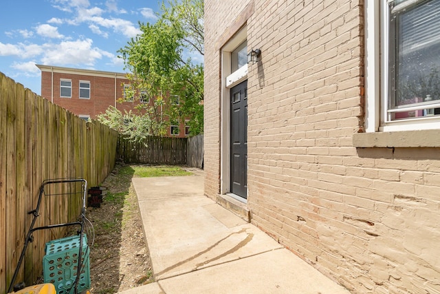 view of side of home featuring a patio, brick siding, and a fenced backyard