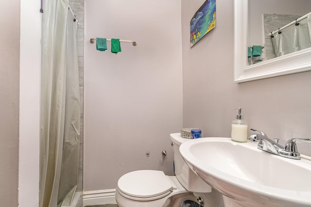 bathroom featuring a sink, a shower with shower curtain, and toilet