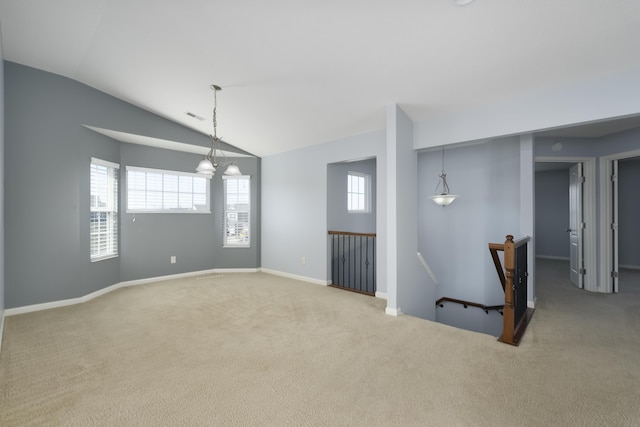 carpeted spare room with baseboards, vaulted ceiling, and visible vents