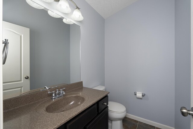 bathroom with baseboards, tile patterned flooring, toilet, and vanity