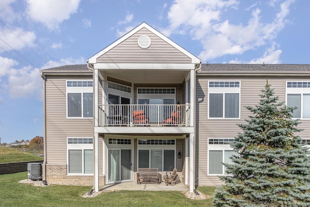 rear view of house with a lawn, a patio area, a balcony, and cooling unit
