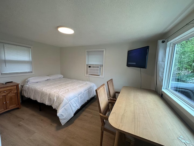 bedroom with a textured ceiling, light wood-style flooring, and cooling unit