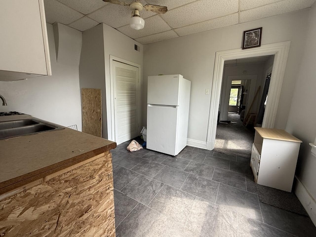 2749 Alexandria Ave, Covington, KY 41015 - kitchen featuring white cabinets, ceiling fan, a sink, a paneled ceiling, and freestanding refrigerator