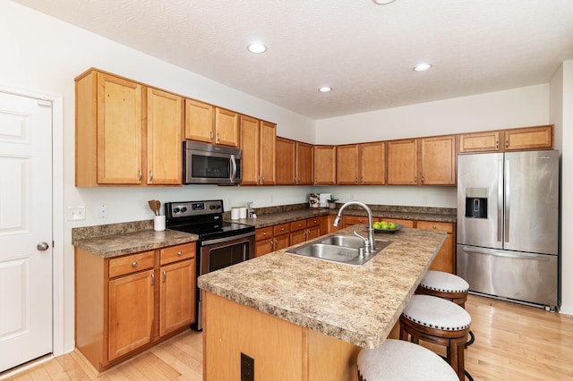 kitchen with light wood-style floors, a breakfast bar area, recessed lighting, a sink, and stainless steel appliances