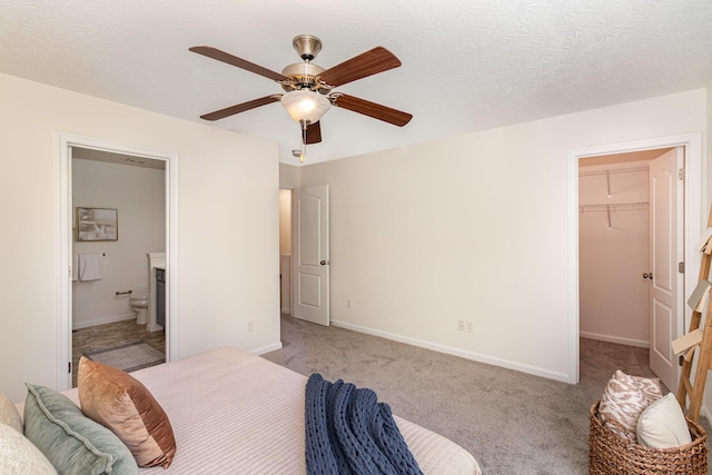 carpeted bedroom with baseboards, a closet, ensuite bath, and a spacious closet