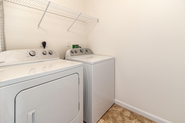 clothes washing area featuring laundry area, baseboards, and washing machine and clothes dryer