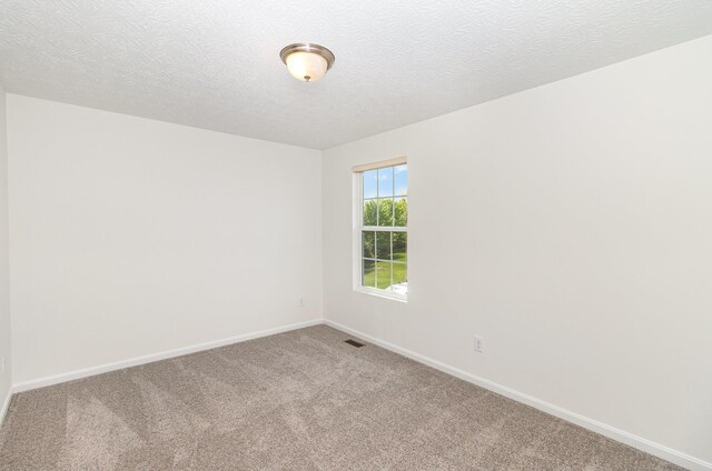 empty room featuring visible vents, carpet flooring, baseboards, and a textured ceiling