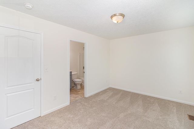 unfurnished bedroom with baseboards, light carpet, and a textured ceiling