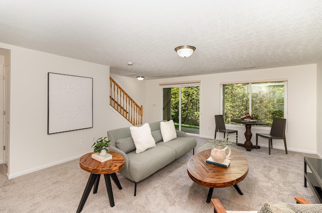 living room featuring light colored carpet, stairs, and baseboards