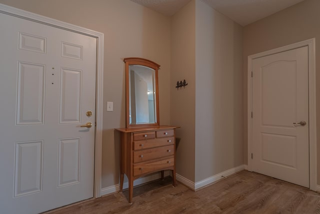 foyer entrance featuring light wood-style flooring and baseboards