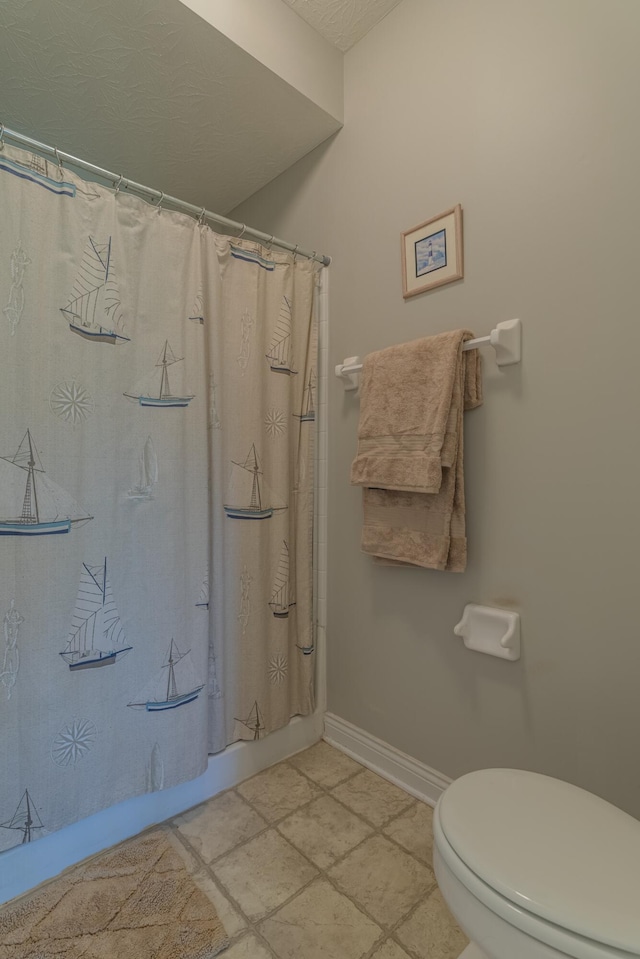 full bath featuring toilet, baseboards, and a shower with shower curtain