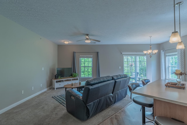 living room with a ceiling fan, baseboards, a chandelier, and a textured ceiling