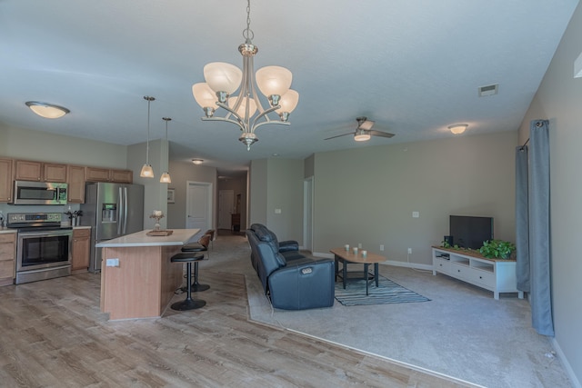 living area with ceiling fan, a chandelier, light wood finished floors, and baseboards