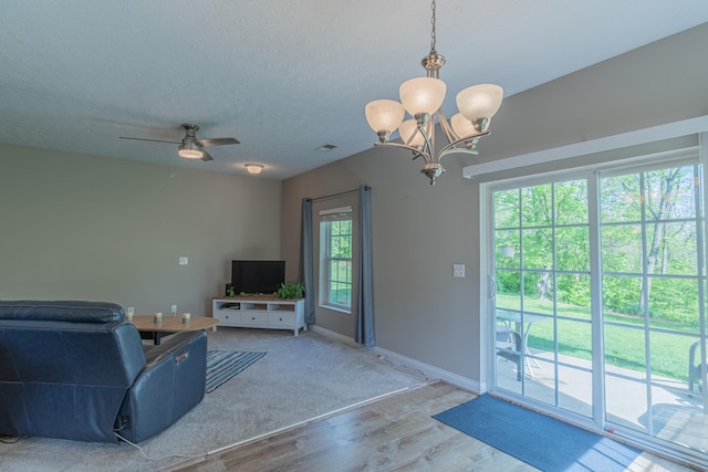 living area with wood finished floors, a chandelier, baseboards, a ceiling fan, and a textured ceiling