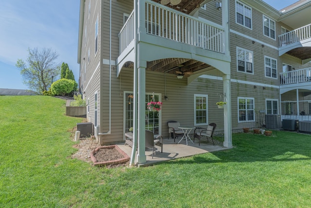 rear view of house with a balcony, ceiling fan, central air condition unit, and a lawn