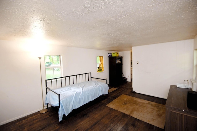 bedroom featuring a textured ceiling, baseboards, and hardwood / wood-style floors