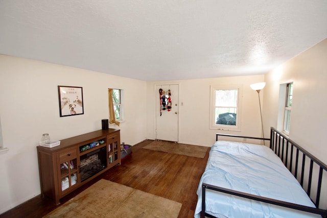 bedroom with a textured ceiling, baseboards, and wood finished floors
