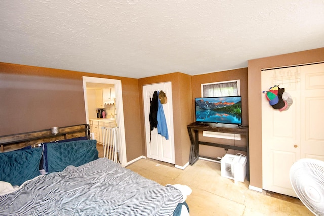 bedroom with baseboards, ensuite bathroom, and a textured ceiling