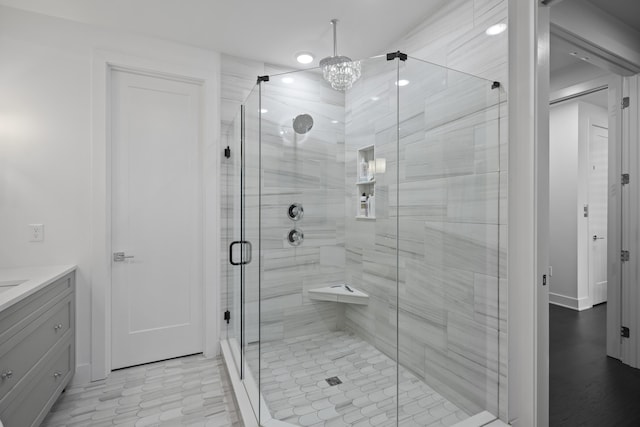 full bathroom featuring vanity, a shower stall, and a chandelier