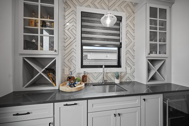 bar featuring decorative backsplash, decorative light fixtures, a sink, indoor wet bar, and beverage cooler