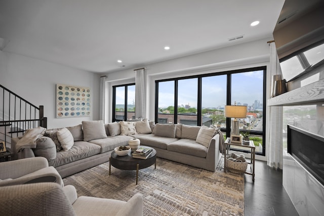 living area featuring dark wood-style flooring, visible vents, a fireplace, stairs, and recessed lighting