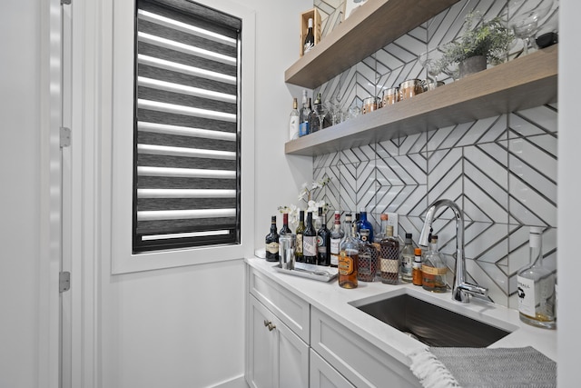 bar featuring a sink, tasteful backsplash, and indoor bar