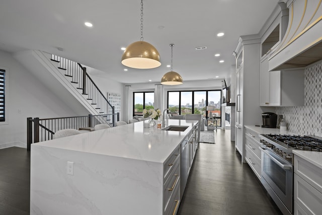 kitchen featuring appliances with stainless steel finishes, a sink, custom exhaust hood, open floor plan, and recessed lighting