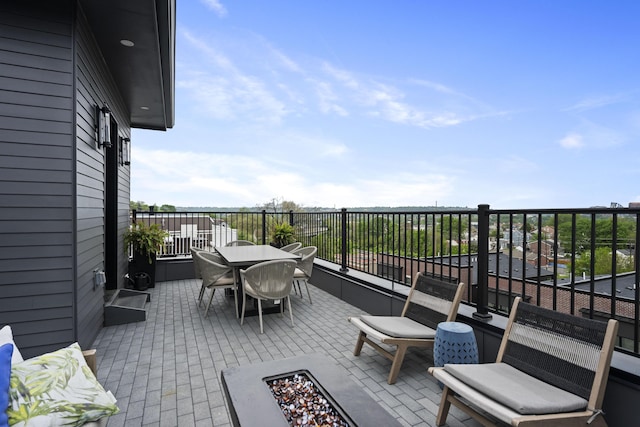view of patio / terrace featuring a balcony, outdoor dining area, and an outdoor fire pit