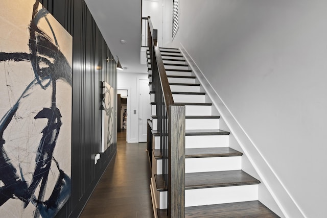 stairway featuring baseboards, wood finished floors, and visible vents