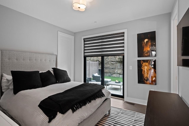 bedroom with baseboards, access to exterior, and wood finished floors