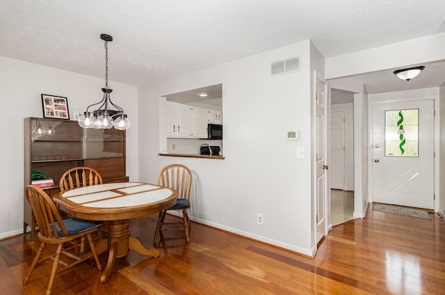 dining space featuring baseboards, visible vents, and wood finished floors