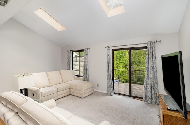 carpeted living room featuring vaulted ceiling with skylight, baseboards, and visible vents