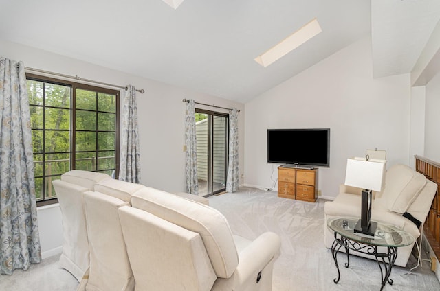 living area featuring baseboards, lofted ceiling with skylight, and light colored carpet