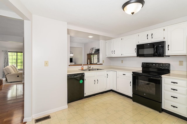 kitchen featuring visible vents, a sink, light countertops, black appliances, and white cabinetry