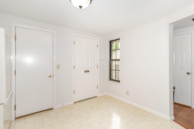 unfurnished bedroom featuring a closet, baseboards, and light floors