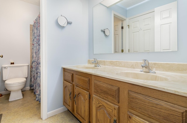 bathroom featuring double vanity, toilet, baseboards, and a sink