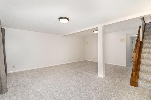 finished below grade area featuring stairway, baseboards, carpet, and visible vents