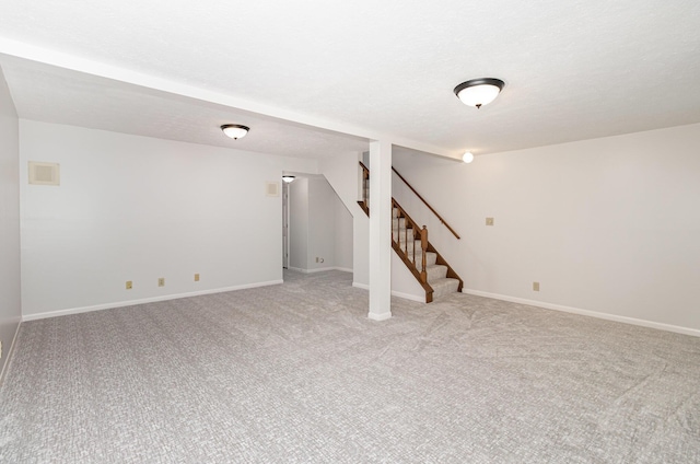 finished basement featuring light colored carpet, baseboards, and stairway