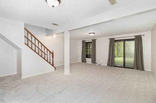 unfurnished living room with carpet floors, stairs, and visible vents