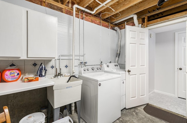 washroom with a sink, washing machine and dryer, and cabinet space
