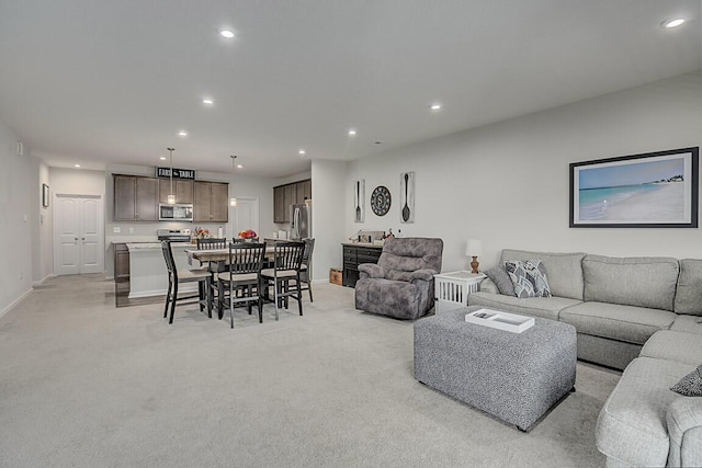 living area featuring baseboards, recessed lighting, and light colored carpet