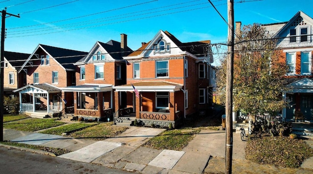 view of front facade featuring a chimney, a porch, and brick siding