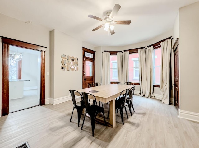 dining area featuring baseboards, visible vents, ceiling fan, and light wood-style floors