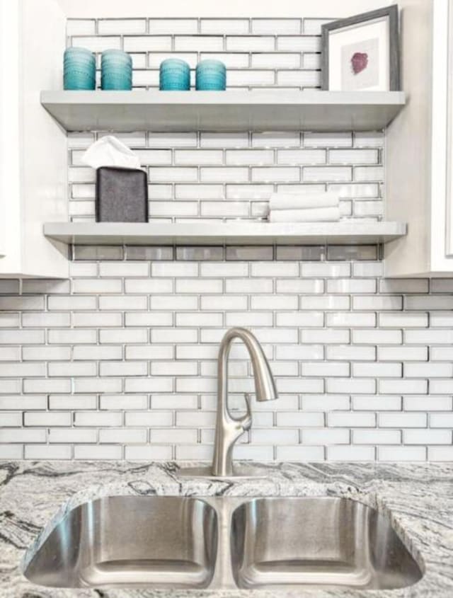 interior details with a sink, decorative backsplash, and open shelves