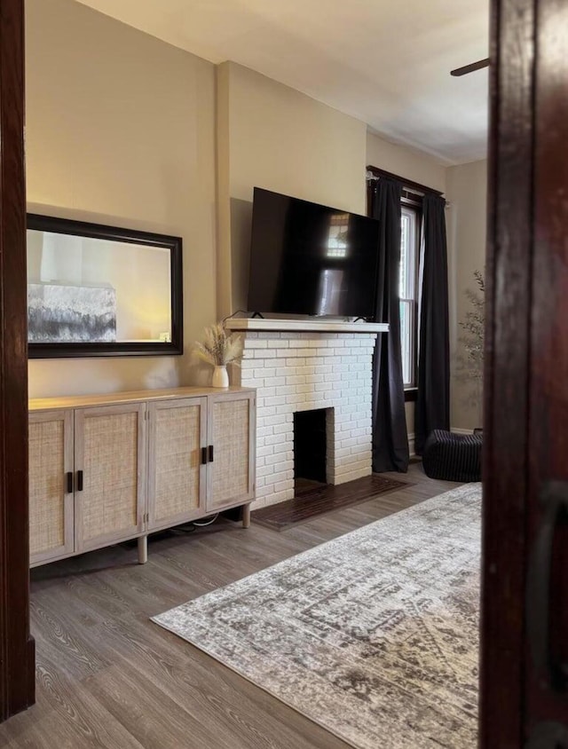 living area with a fireplace, a ceiling fan, and wood finished floors